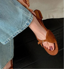 Brown sandal worn with a denim skirt on a neutral background