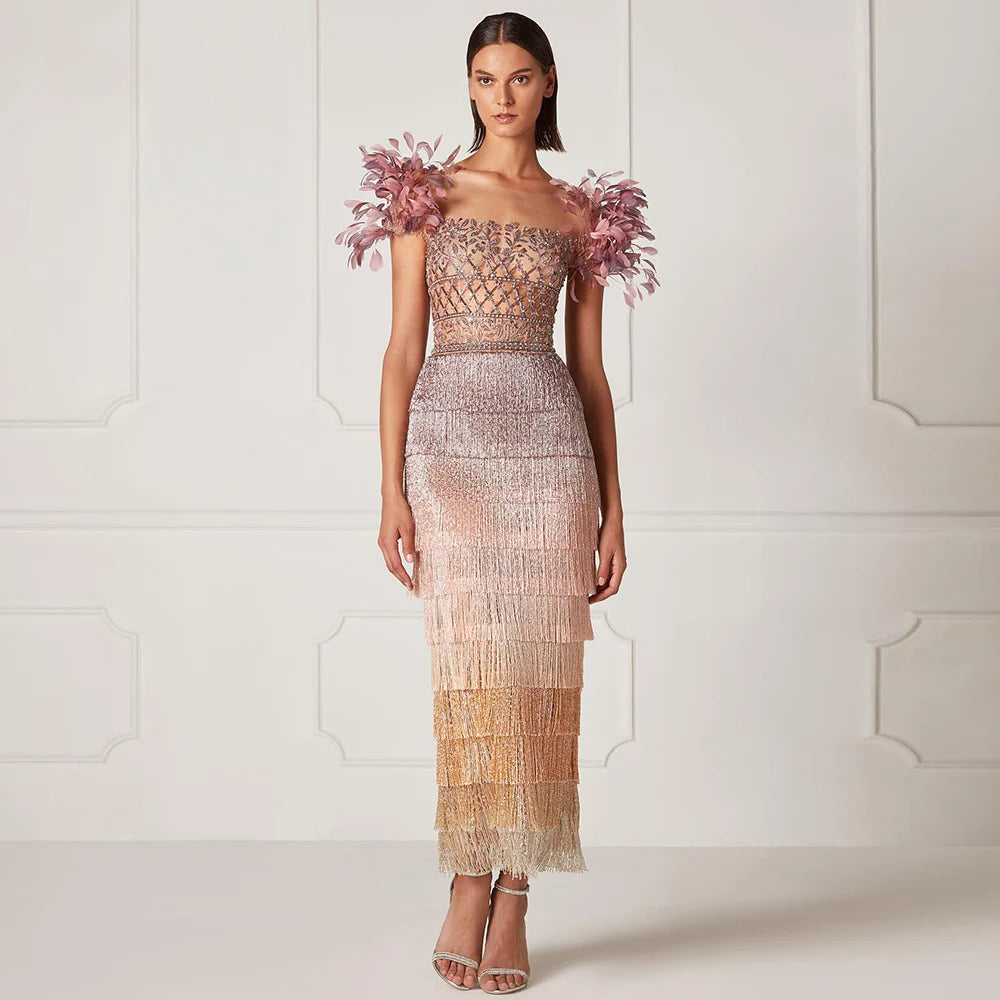 A woman modeling a lilac feather and tassel evening gown with a trumpet silhouette.