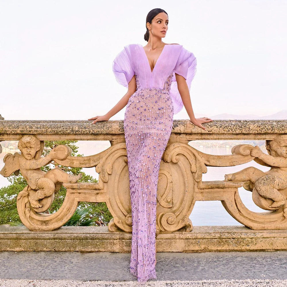 A woman modeling a lilac mermaid gown with a sweetheart off-shoulder neckline.