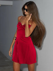 Woman wearing little red dress with hand in flowing hair  for party plans with a plain background.