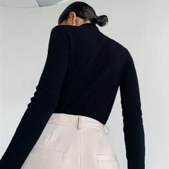 Side angle showing the slim fit and long sleeves of the knit sweater with a smooth, structured drape.