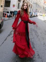 Woman in a  tiered ruffle red maxi dress moving gracefully on the street standing on a city street.