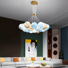 A pendant LED light fixture with glass balls in various shades of blue, suspended from the ceiling over a modern living room setup with a white sofa, orange pillows, and a wooden coffee table.