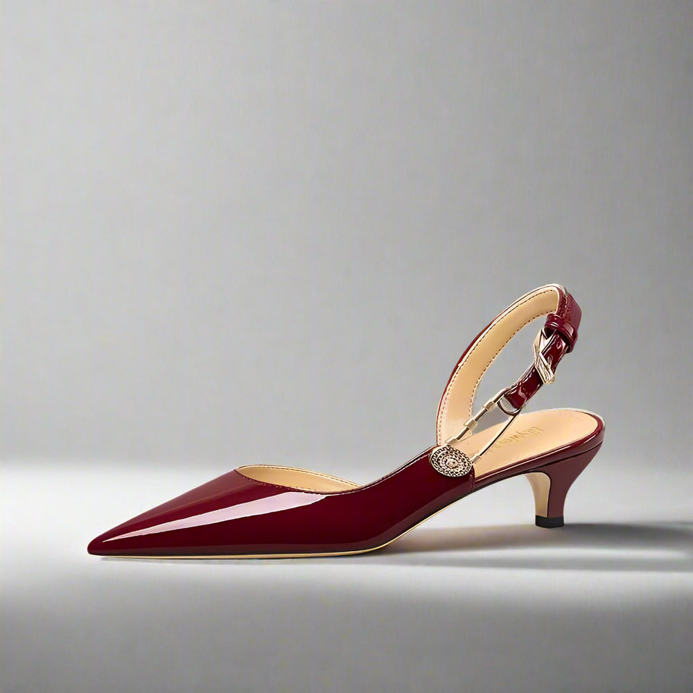 Maroon patent leather slingback sandal with metal buckle styled for banquet and dress events on a light gray background