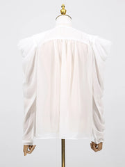 Detail view of the blouse sleeve in motion, showcasing the tie-up design and lightweight fabric flow.