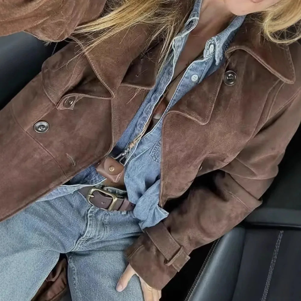 A woman wearing a mid-length trench coat on the city steps