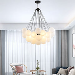  A frosted glass chandelier with a silver iron finish hangs from the ceiling of a living room. The chandelier has a white color, and it appears to be dimly lit, enhancing the cozy ambiance of the room.