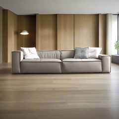 Modern design wooden frame leather sofa with a metal accent, displayed in a bright living room setting with a lighted reading lamp in the background.
