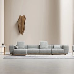 A modern L-shaped metal and genuine leather sofa set with sleek design, featuring gray upholstery and metal legs, placed in a minimalist living room setting