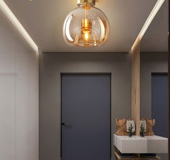 A pendant ceiling light with glass balls and metallic halide bulbs hang over a modern dining area with dark walls and light-colored furniture.