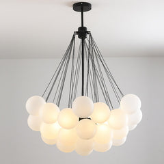 A frosted glass chandelier with a silver iron finish hanging from the ceiling. The chandelier has a white color, and it appears to be dimly lit, enhancing the cozy ambiance of the room.