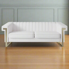 A beige velvet long couch Chesterfield sofa with a chaise, displayed in a room with a grey wall and a wooden floor.