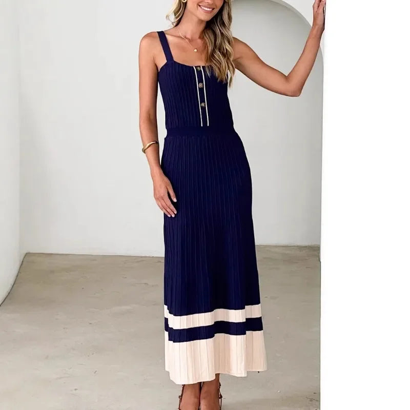 Woman wearing a navy knitted contrast patchwork pleated dress with metal buttons for juniors against a plain background
