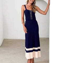 Woman wearing a navy knitted contrast patchwork pleated dress with metal buttons for juniors against a plain background