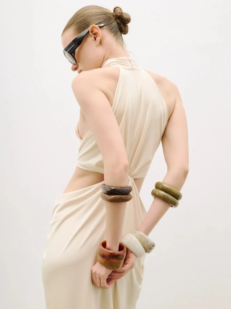 Upper-body detail highlighting the high neckline and bare-shoulder halter shape, styled with sleek accessories on a minimal backdrop.