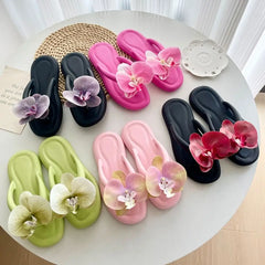 Colorful flip-flops with floral decorations on a round white table.