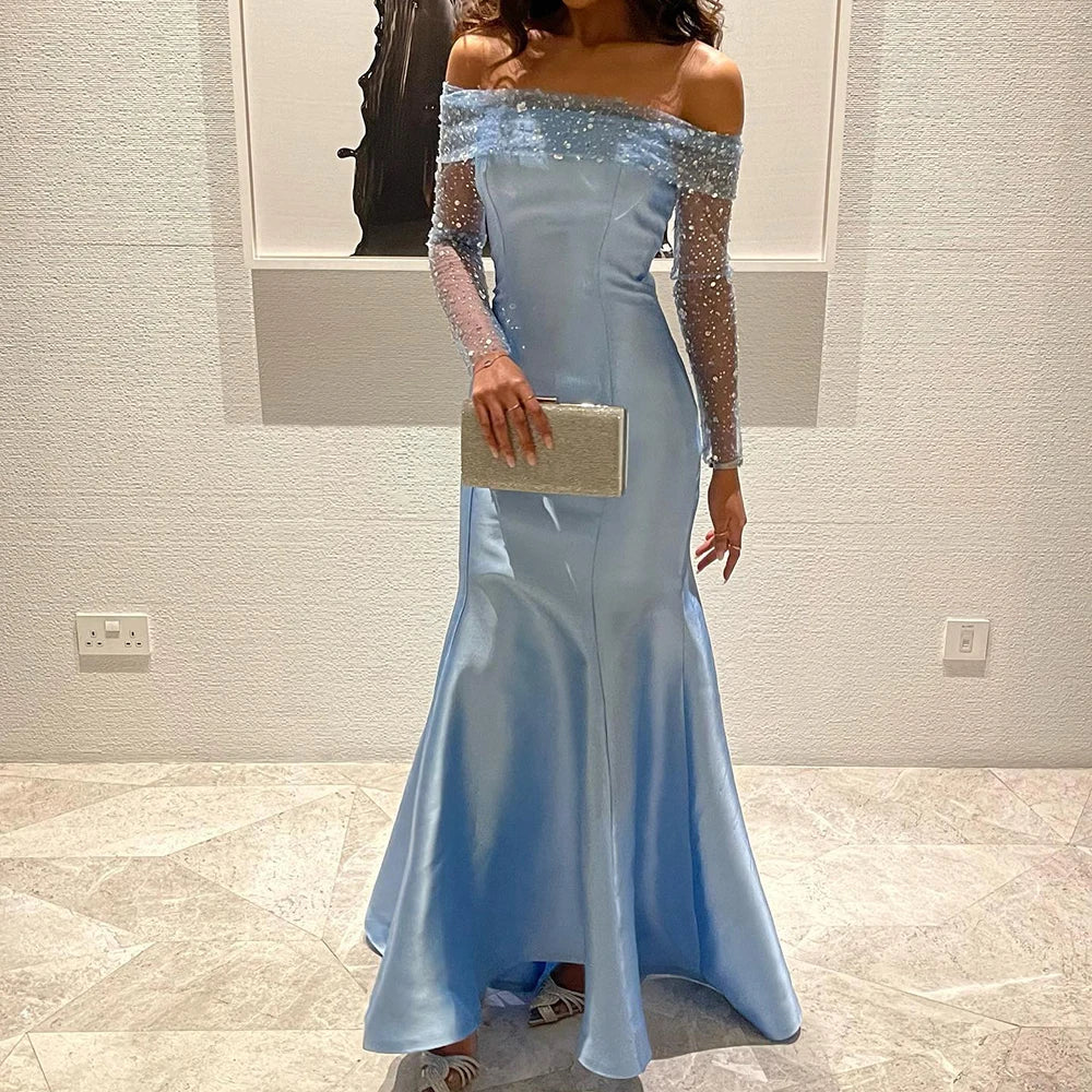 A woman wearing an elegant off-shoulder blue mermaid gown with long sleeves.