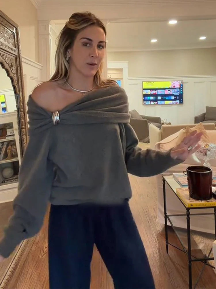 Off-shoulder cropped sweater top paired with high-waist pants and a shoulder bag