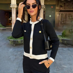 Woman in a  office lady autumn button sweater with O-neck in black and white, sunglasses, and a handbag in an outdoor setting.