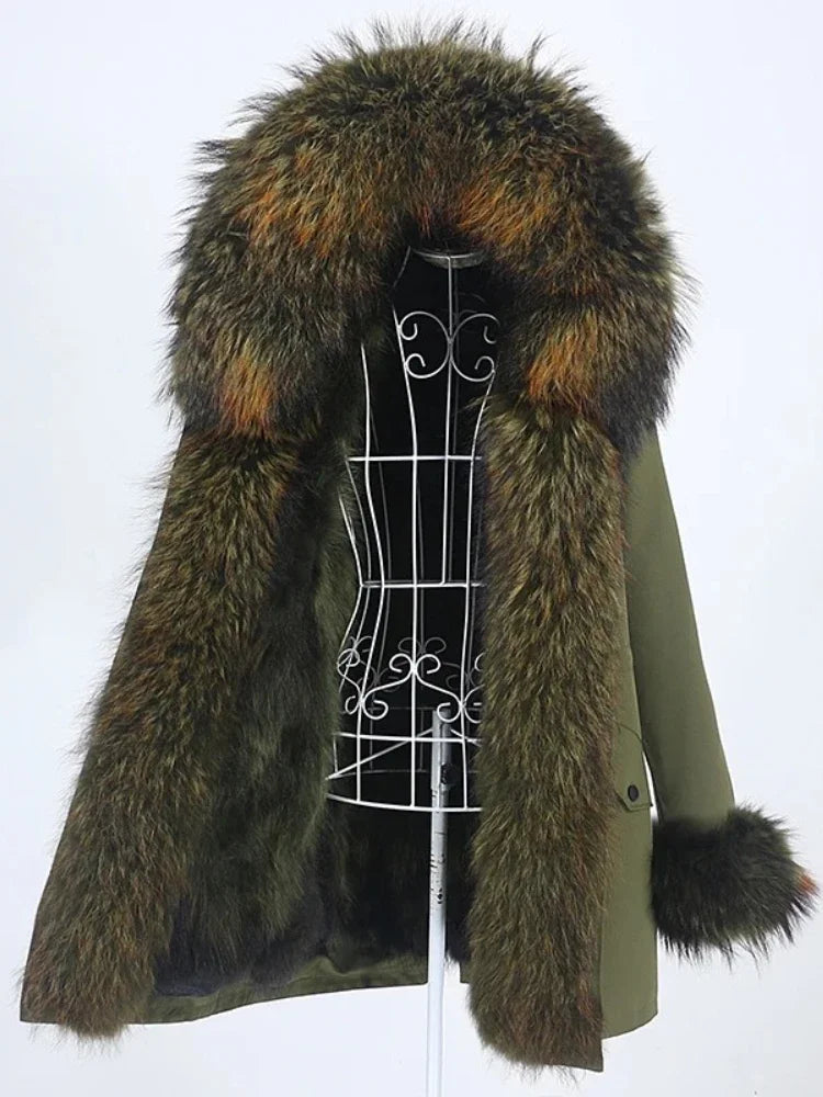Long parka on a dress form with an oversized fur-trim hood framing the opening and plush fur cuffs against a white backdrop.