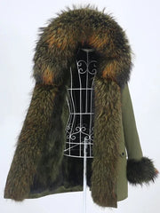 Long parka on a dress form with an oversized fur-trim hood framing the opening and plush fur cuffs against a white backdrop.