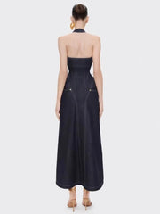 Woman wearing a open back denim-look maxi styled with statement earrings on a white background