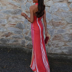Side view of a woman in a red and white striped dress standing against a stone wall.
