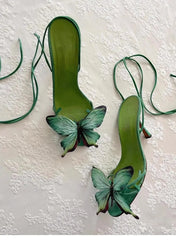 Green high-heeled shoes with butterfly decorations on a textured white background