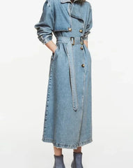 Model wearing long belted denim trench coat in blue