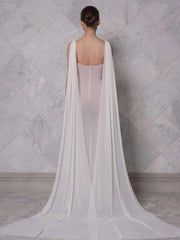 Patchwork slim party cocktail dress displayed for formal occasions. A woman wearing a white gown with a long train against a marble wall.