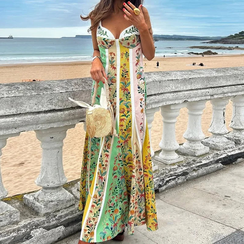 A woman wearing a patchwork spaghetti-strap maxi dress standing on a beach with an ocean view.