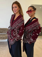 Street-style outfit featuring a burgundy patterned cardigan with wide-leg trousers and sunglasses, creating an effortless boho-meets-city silhouette.
