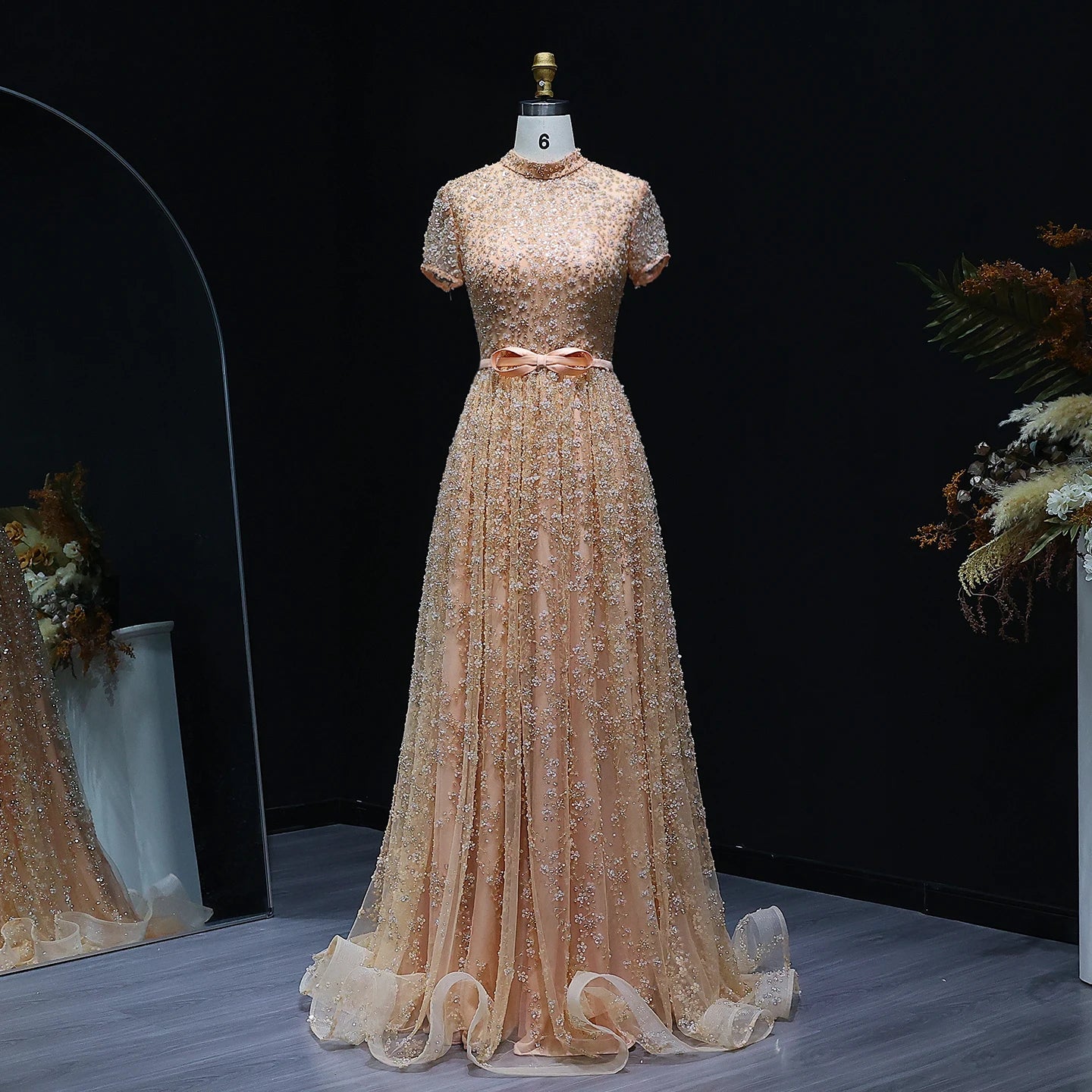 Beige evening gown on a mannequin against a dark background