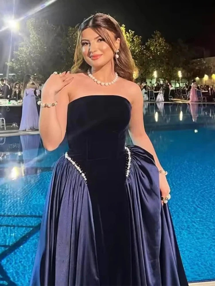 Close-up texture of a strapless velvet gown showing pearl beading and soft sculpted bodice.