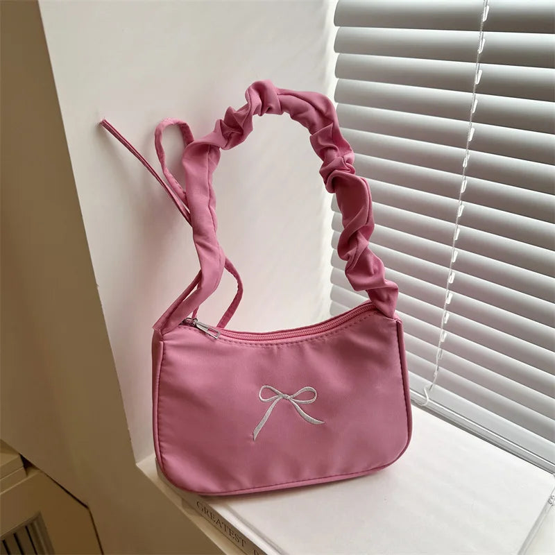 Pink square shoulder bag with embroidered bow and pleated strap