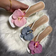 White flats with pink, blue, and purple flowers on a textured surface