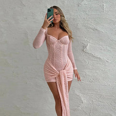 Woman wearing a pink lace dress against a textured white wall