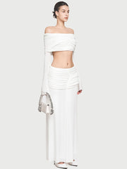 Woman holding a small handbag while wearing a coordinated top and long skirt