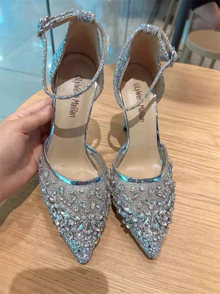 Pointed toe silver sandal with crystals styled for luxury wedding partieson a wooden surface