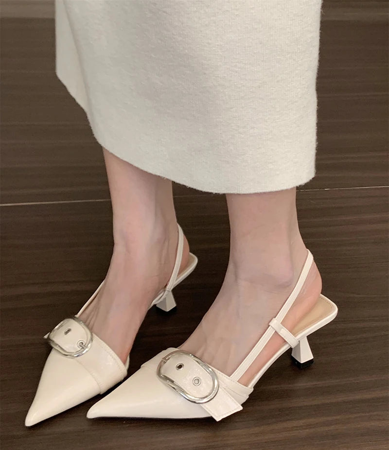 White pointed toe slingback sandals with buckle strap on wooden floor