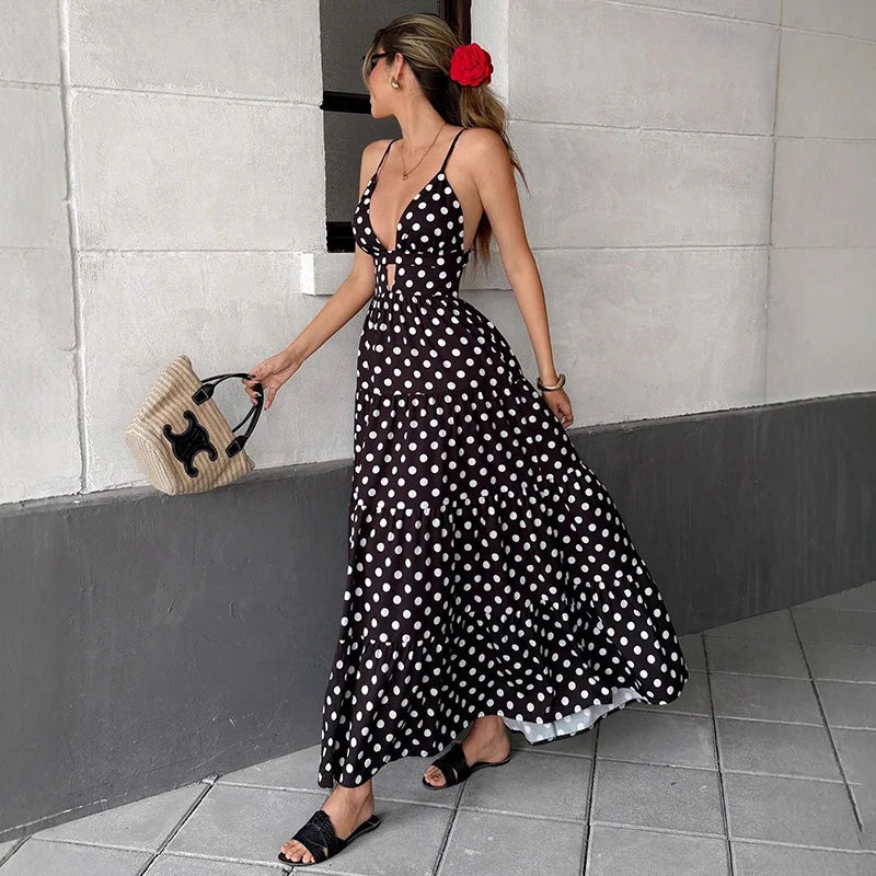 Woman walking in black polka dot chiffon maxi dress with woven bag