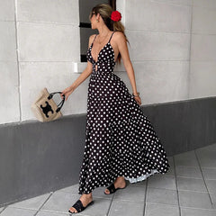 Woman walking in black polka dot chiffon maxi dress with woven bag