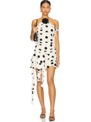 Woman wearing a polka dot halter mini dress with backless neckline and ruffle hem on a white background.