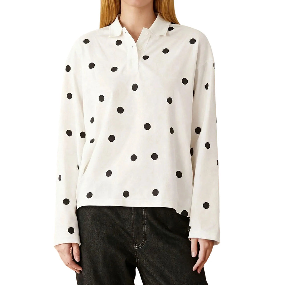 Polka dot polo shirt styled with dark trousers for a relaxed, vintage-inspired daytime look.