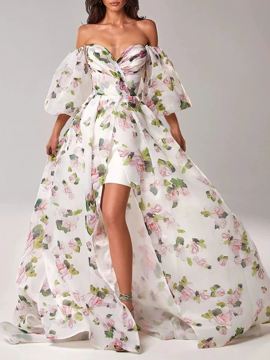A woman modeling a printed maxi dress with a slash neckline and puff sleeves.