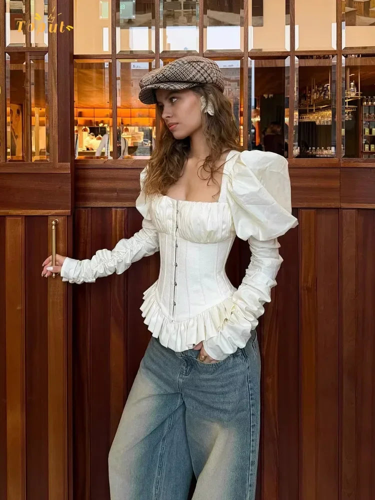 Three-quarter angle highlighting the dramatic puff sleeve shape and square neckline of the ivory blouse, creating a sculpted, editorial silhouette.