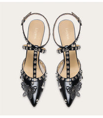 A woman modeling a punk rivet sandal with a butterfly and a thin heel.