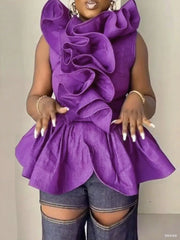 Person wearing a purple ruffled top with denim shorts on a plain background