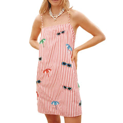 Woman wearing a cutout beach dress with spaghetti straps and fun retro aesthetic with sunglasses and palm tree designs on a white background