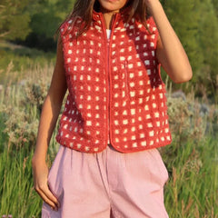 Person wearing a red checkered vest in a natural setting